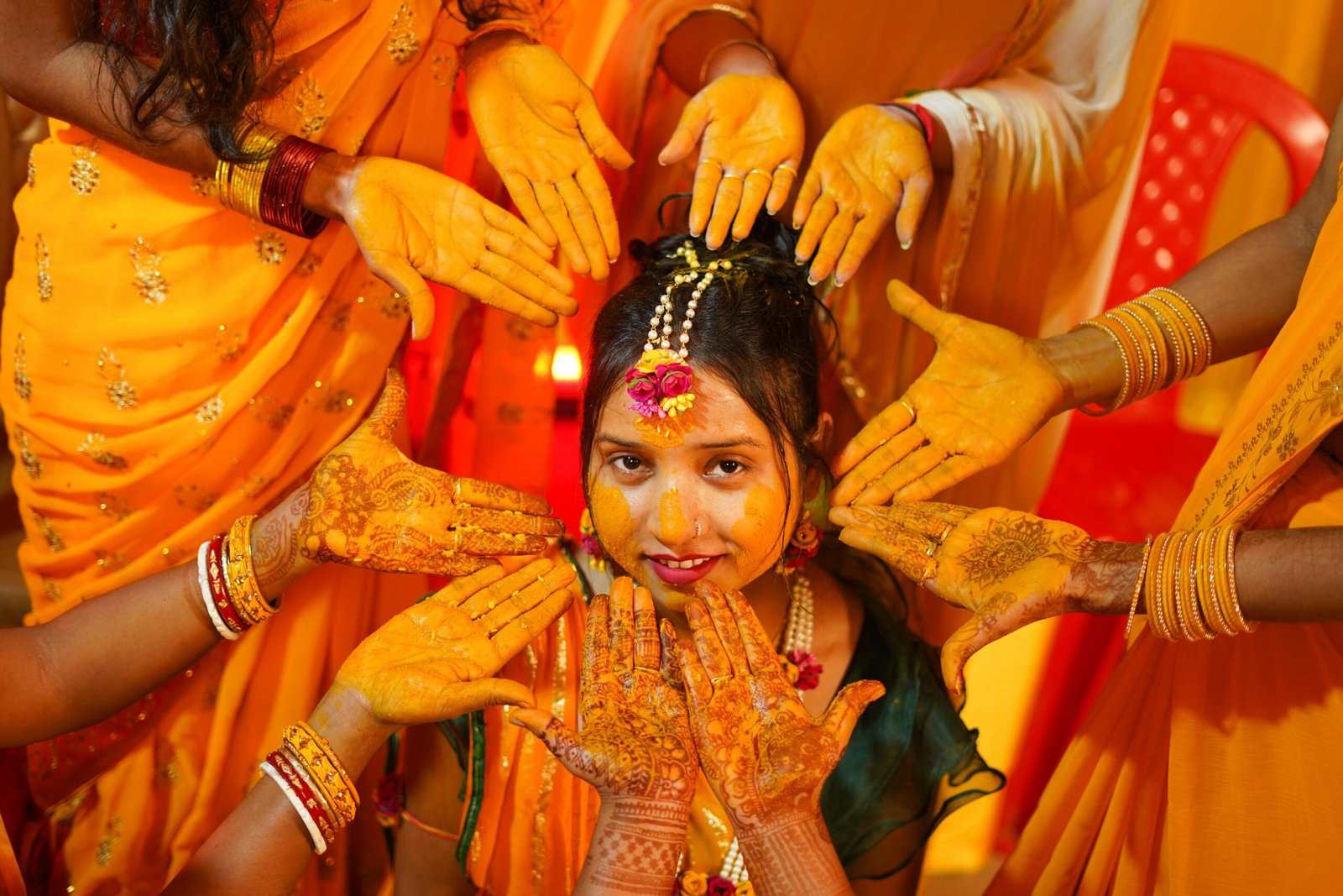 Colorful Indian bride during Haldi ceremony with friends applying turmeric for tradition.
